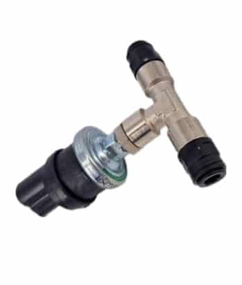 Ein Dieseldrucksensor, ein zylindrischer, schwarz-silberner Drucksensor, ist mit schwarzen Kunststoffsteckanschlüssen an einem T-Stück aus Metall befestigt.