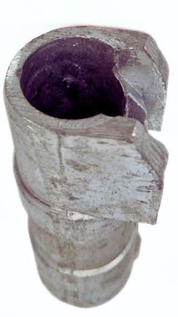 Nahaufnahme einer Standrohrkupplung, eines zylindrischen Metallbauteils, das an der oberen Kante einen großen Ausbruch aufweist und eine raue, beschädigte Oberfläche erkennen lässt.