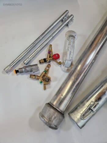 Die Rohreinheit 100 Nase/Schlaufe sowie verschiedene Metallrohre, Ventile und Armaturen sind auf einer weißen Fläche angeordnet.