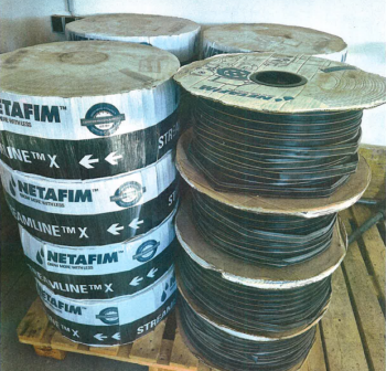 Mehrere große Spulen mit NETAFIM Streamline X 22080 Bewässerungsschläuchen sind auf einer Holzpalette in einem Innenraum gestapelt.