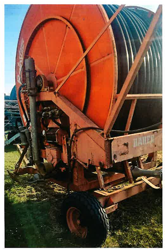 Der Bauer Rainstar 90/430m ist eine große orangefarbene Schlauchtrommel auf einem fahrbaren Gestell, die im Freien auf einer Wiese aufgestellt wird und über einen aufgewickelten schwarzen Schlauch und sichtbare mechanische Komponenten verfügt.