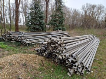 Vielfalt an Beregnungsteilen lagert im Freien auf dem Boden, umgeben von Bäumen und Vegetation.